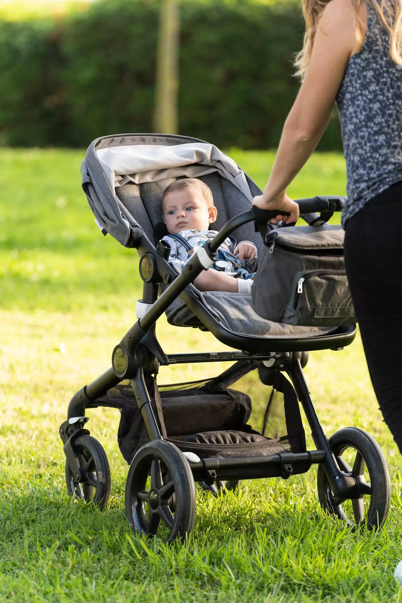 Mother and son walking with the baby stroller in the park