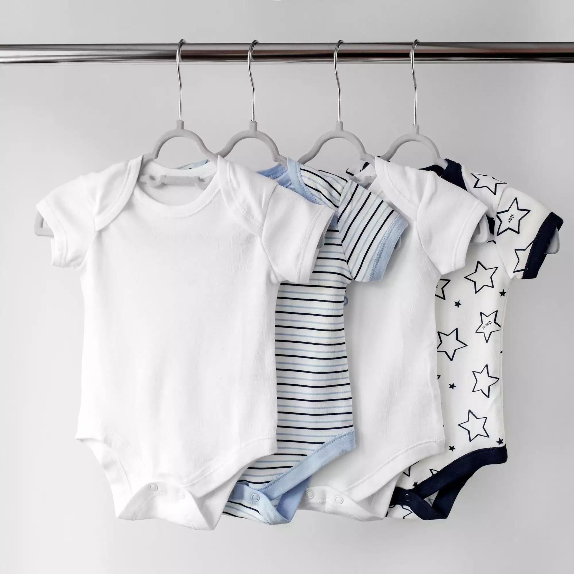 Set of beautiful clothes for newborn on hangers. Copy space. Concept of clothes, motherhood, fashion